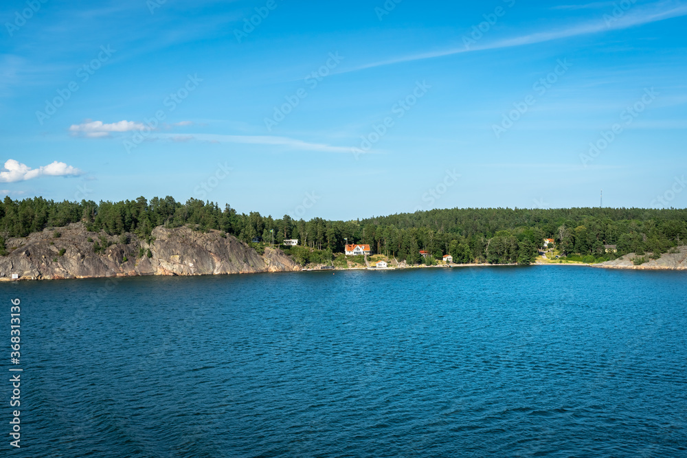Amazing panorama of blue Baltic sea bay. View from the top of cruiser ship. Rocky shores of Scandinavia with colorful old traditional houses. Forest pine islands. 