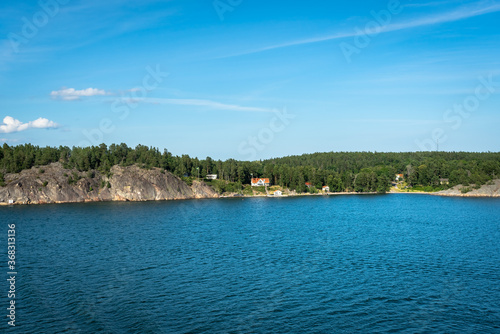 Amazing panorama of blue Baltic sea bay. View from the top of cruiser ship. Rocky shores of Scandinavia with colorful old traditional houses. Forest pine islands. 