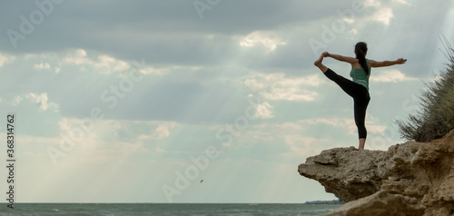 Yoga outdoors on a rocky beach. Young woman practicing yoga on a rocky seaside