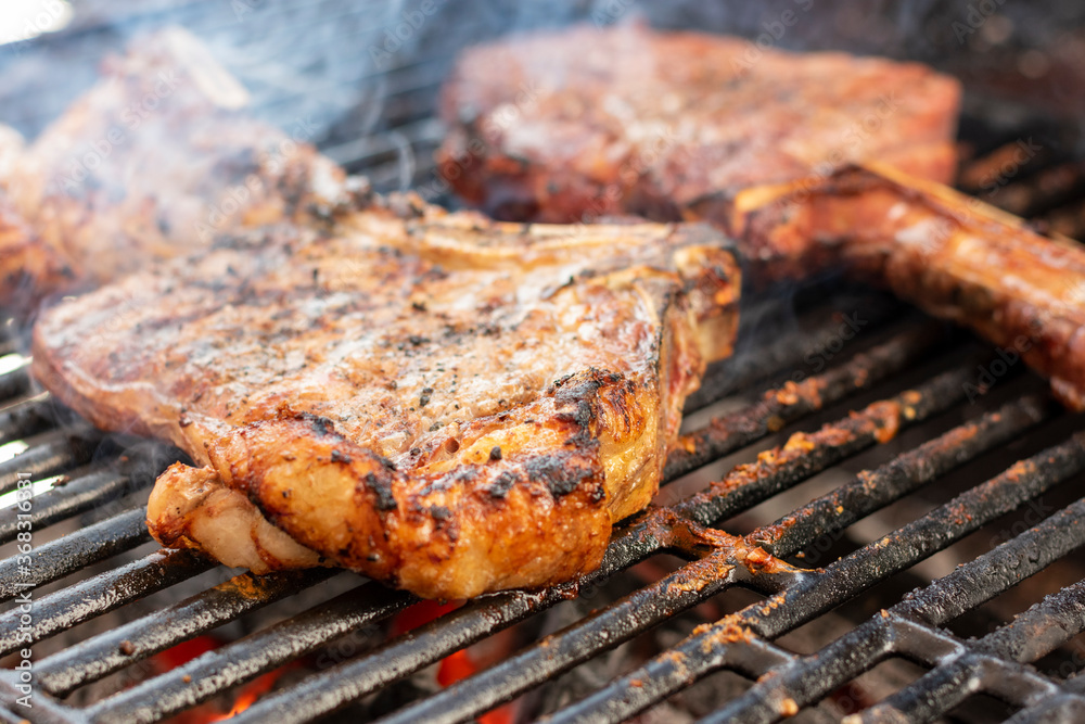 manos preparando distintos cortes en el asador y parrilla. tomahwk , rib eye , new york tuetatons con sal y mienta manos preparando distintos cortes en el asador y parrilla. tomahwk , rib eye , new york tuetatons con sal y mienta