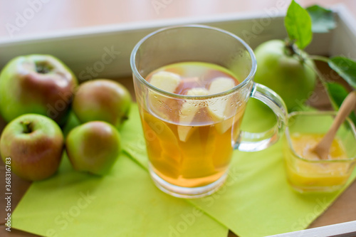 Apfeltee mit frischen Apfelst  ckchen und Honig auf einem Tablett