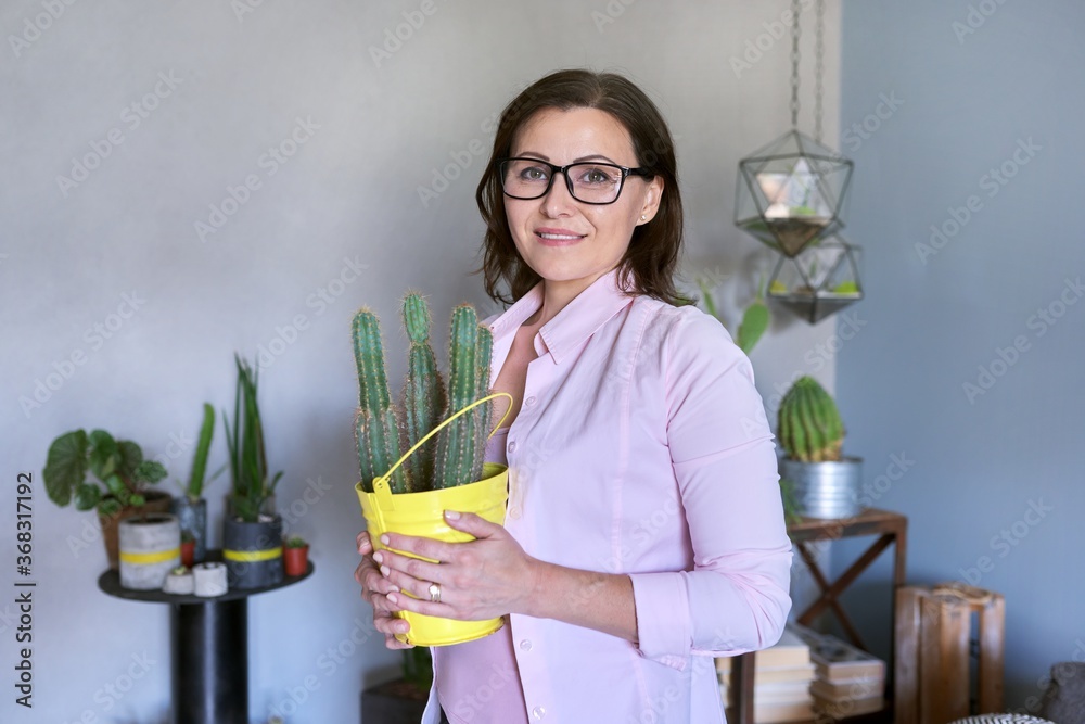 Portrait of mature business woman with cactus in pot, office interior background Portrait of mature business woman with cactus in pot, office interior background