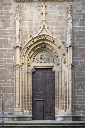 Heavy wooden door. Ancient gate on the facade of a stone building. The architecture of medieval Spain. Streets of Pamplona. Catholic Church. Massive door with a lock.