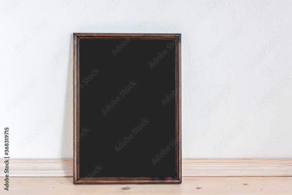 A dark frame stands on a wooden countertop against a light wall. Presentation design elements. Template to insert.