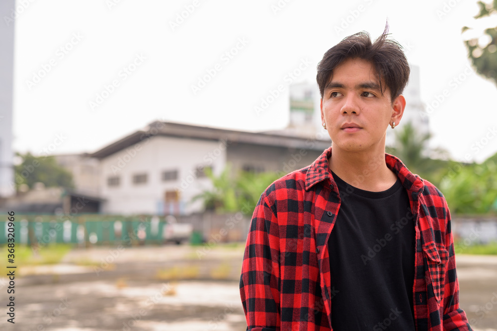 Fototapeta premium Young handsome Asian hipster man in the city streets outdoors
