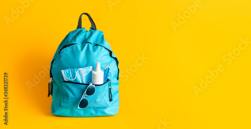 Back to school in pandemic. School backpack with face masks and disinfectant.