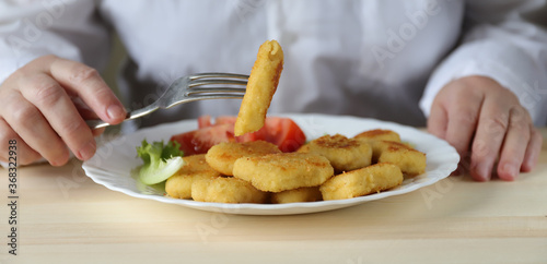 fast food woman eating with a fork nuggets that are on a white plate