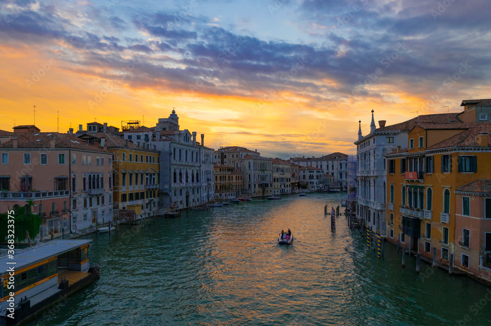 A wonderful evening shot of the Canal Grande and its palaces seen from the Accademia Bridge or Ponte dell'Accademia. Sunset with orange and blue clouds reflecting on the water. Venice, Italy.