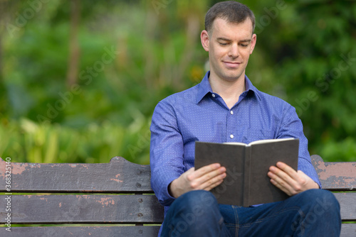 Portrait of businessman reading book at the park