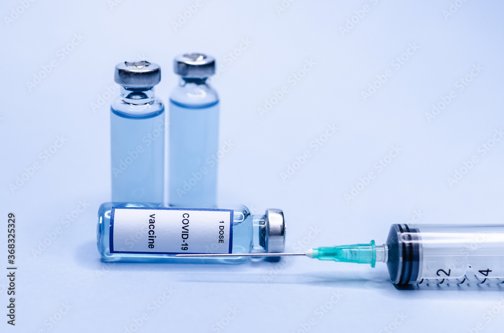 Coronavirus vaccine in glass vials with a syringe on a blue background. Coronavirus vaccine in glass vials with a syringe on a blue background.
