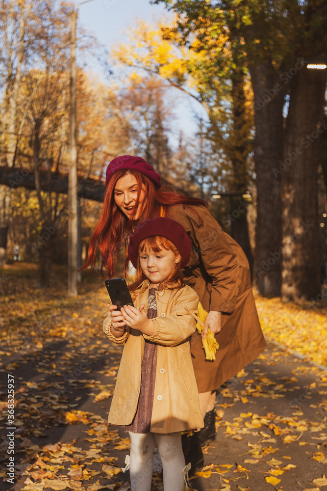 Cheerful and smiling ginger young adult mother in the park having fun with little daughter Cheerful and smiling ginger young adult mother in the park having fun with little daughter
