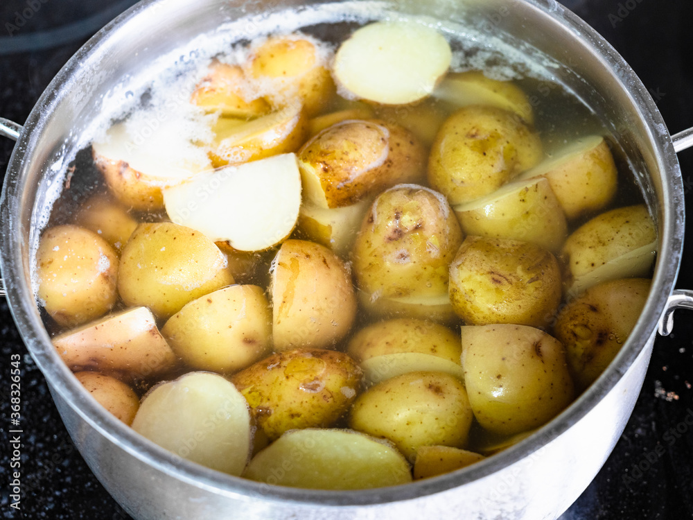 above view of young potatoes in their skins are cooked in steel pan on electric stove at home kitchen