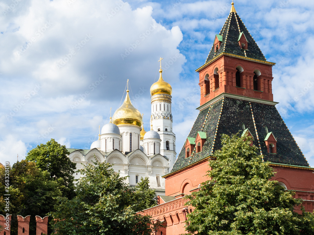 view of Kremlin Wall with Taynitskaya Tower and Cathedral of the Archangel and Ivan the Great Bell Tower during city sightseeing tour on excursion bus in Moscow city on summer day