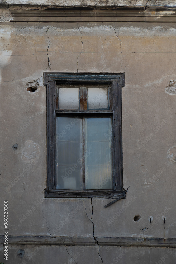 Aged closed window in wall with cracks and holes of abandoned house in Athens Aged closed window in wall with cracks and holes of abandoned house in Athens