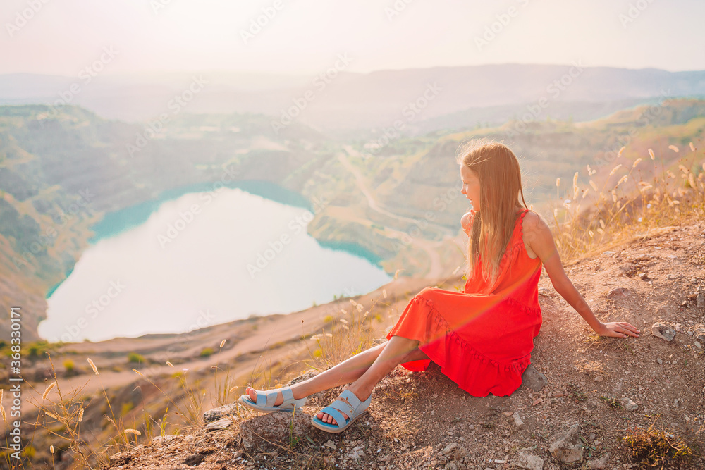 Little girl near the lake at the day time with amazing nature on background Little girl near the lake at the day time with amazing nature on background