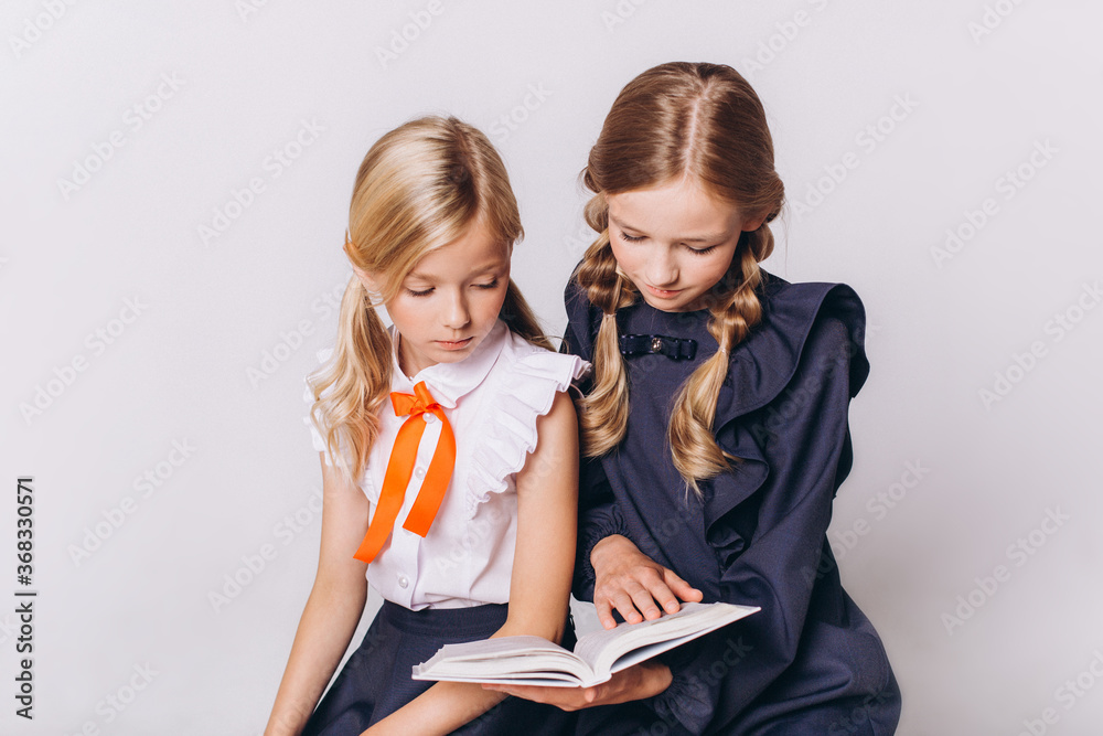 Back to school. Cute adorable caucasian blondie girls in school uniform on white background