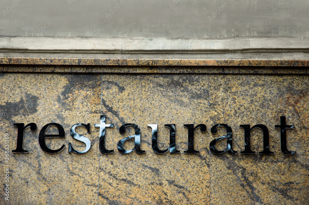 Generic restaurant advertisment in form of black shiny text on marble facade