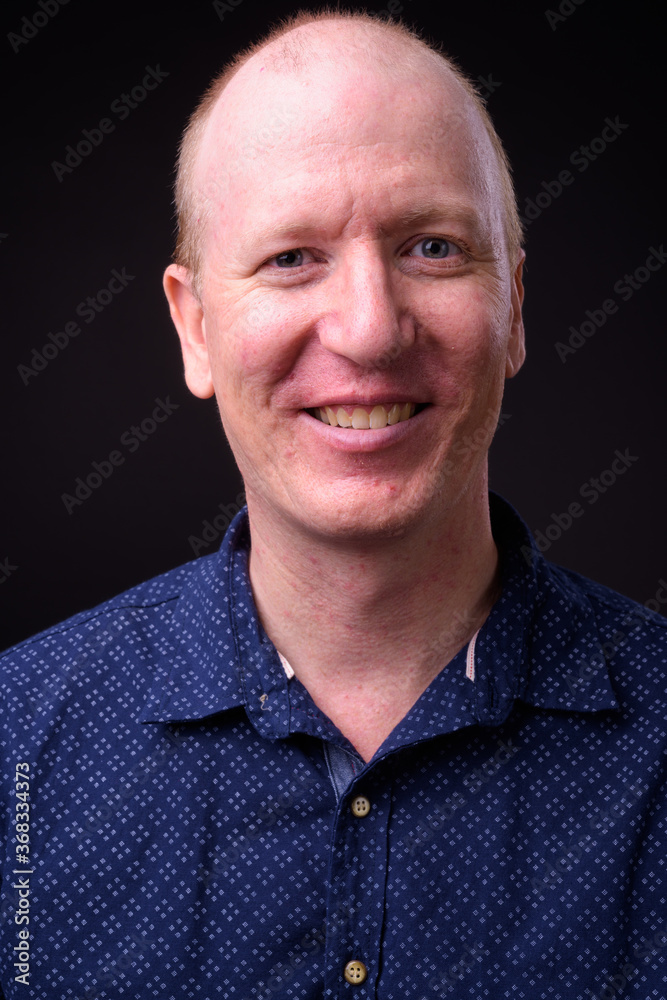 Fototapeta premium Face of happy bald businessman smiling and looking at camera