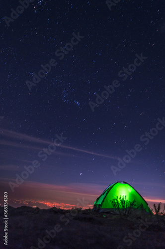 Acampando en la cima de la montaña observando la ciudad de Puebla con un cielo estrellado con la constelación de orión 