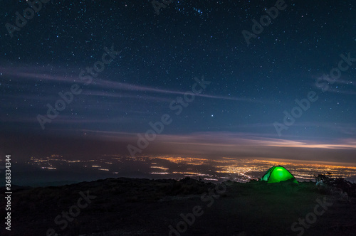 Acampando en la cima de la montaña observando la ciudad de Puebla con un cielo estrellado con la constelación de orión 