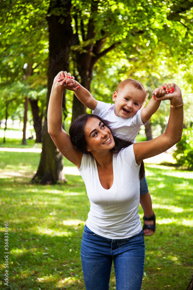Fototapeta premium young pretty brunette mother with little cute boy walking in park happy smiling, lifestyle people concept