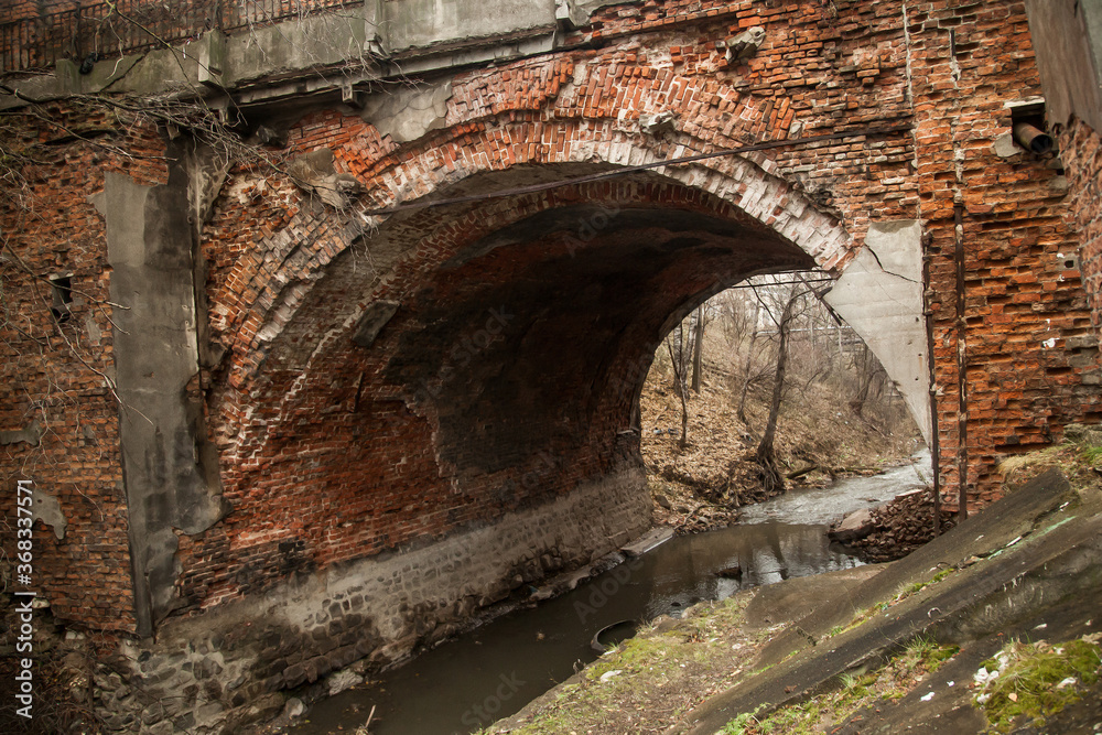 Old crumbling brick bridge over a small river