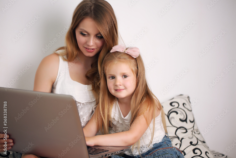 young mother works with her daughter on the pc at home young mother works with her daughter on the pc at home