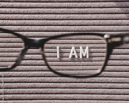 Top view on letterboard with words I AM through eyeglasses. Flat lay concept of psychological self-regulation or gender identity. Social psychological issue. Closer look on psychological problems. photo