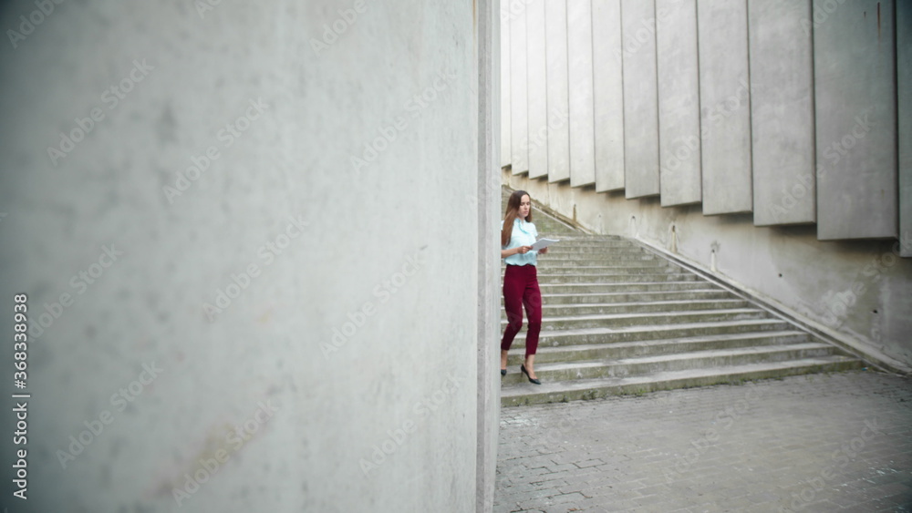 Businesswoman reading business documents outdoors. Female worker walking for job Businesswoman reading business documents outdoors. Female worker walking for job