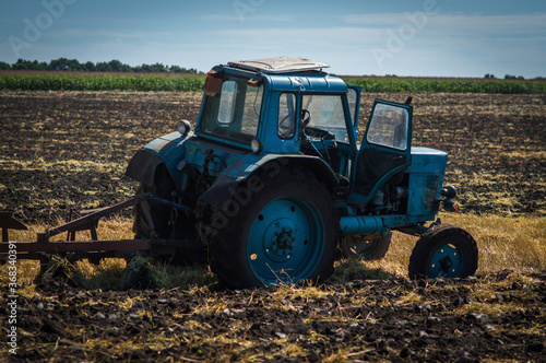 blue old tractor plowing field side view