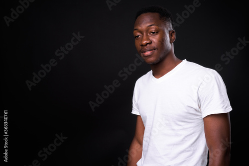 Young handsome African man against black background
