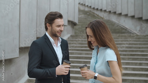 Cheerful coworkers talking in city. Woman and man having meeting after work