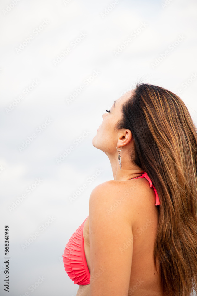 Beautiful young brunette on the river. Adult women enjoy summer day. Women with long hair in swimsuit look at sky Beautiful young brunette on the river. Adult women enjoy summer day. Women with long hair in swimsuit look at sky