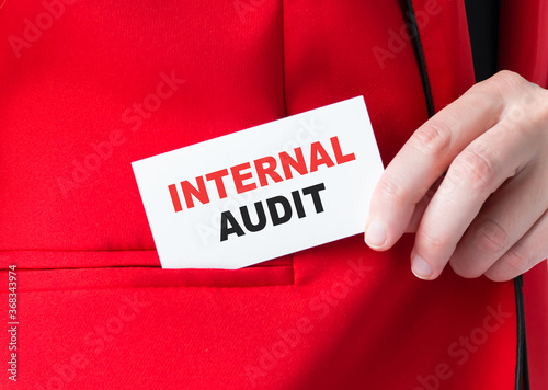 Businessman putting a card with text INTERNAL AUDIT in the pocket