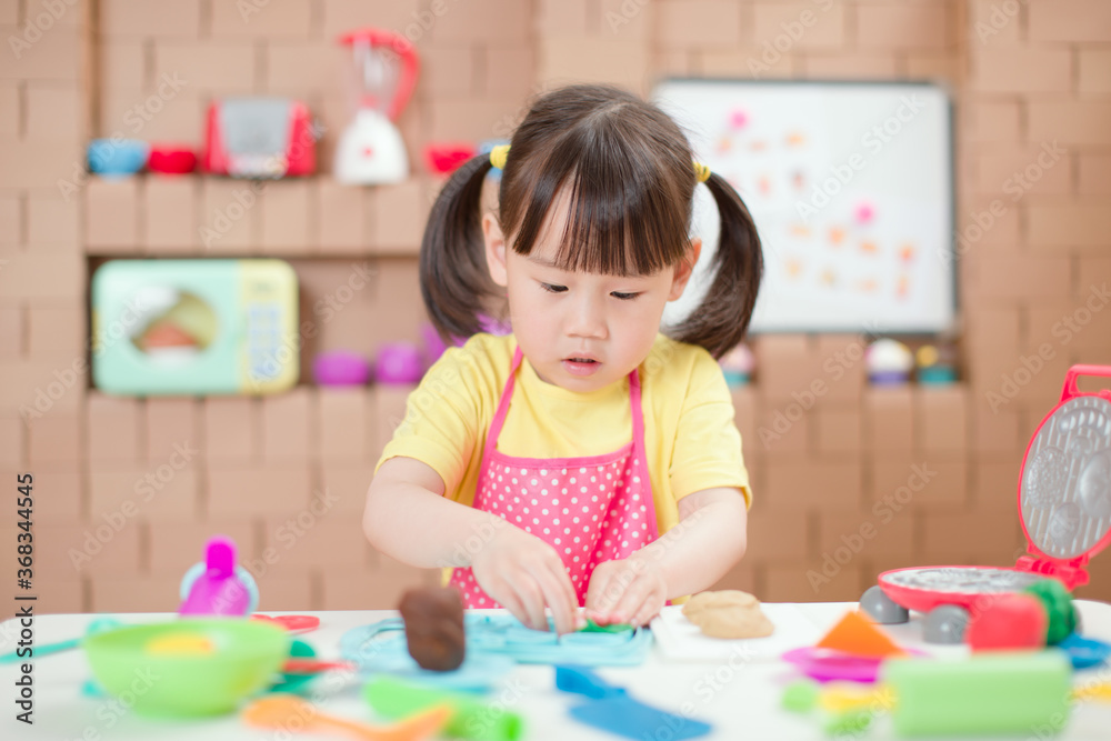 young girl pretend play food preparing role against cardboard blocks kitchen background young girl pretend play food preparing role against cardboard blocks kitchen background