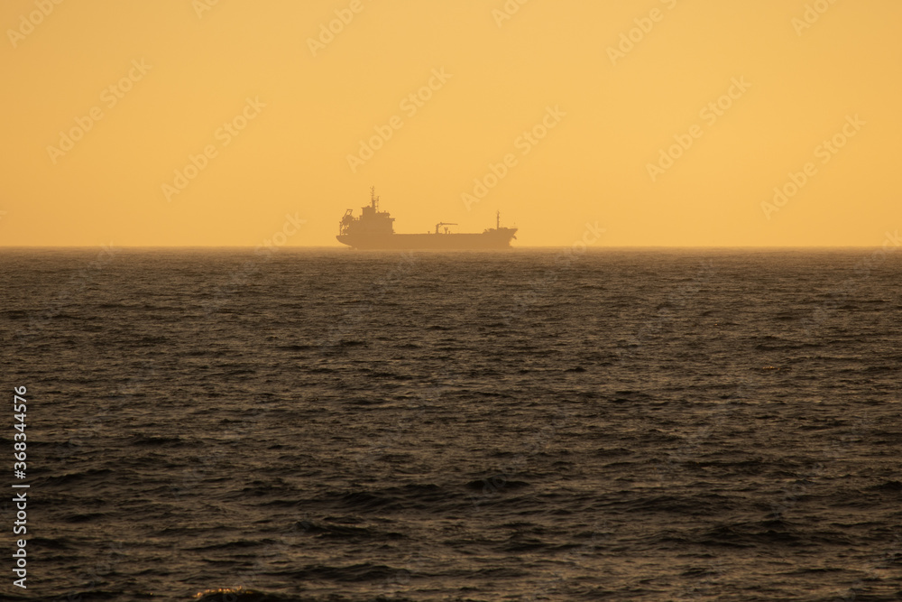 Large cargo ship sailing smoothly in the ocean during a wonderful sunset, Portugal Large cargo ship sailing smoothly in the ocean during a wonderful sunset, Portugal