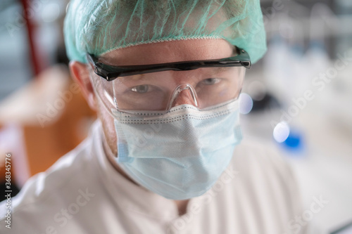 A scientist wearing protective gear looking to the camera in a modern laboratory.