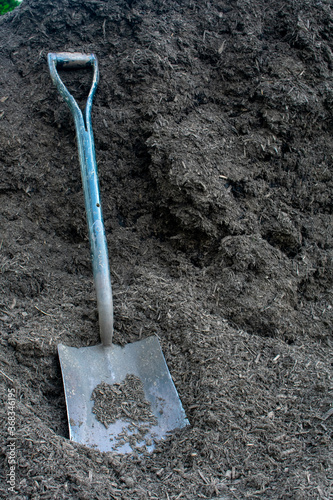 A Large Square Shovel Resting on a Pile of Mulch