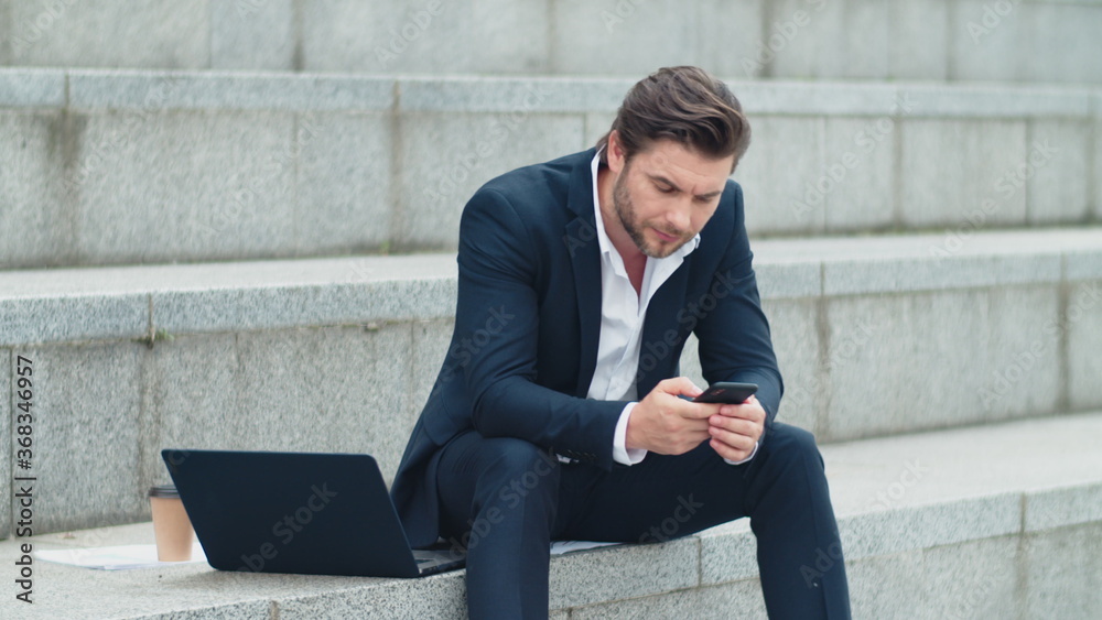 Businessman texting on cellphone at street. Professional working on smartphone Businessman texting on cellphone at street. Professional working on smartphone