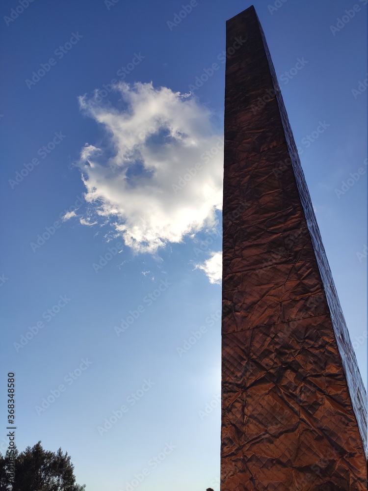 columna en piedra y cielo azul con nube cruzando