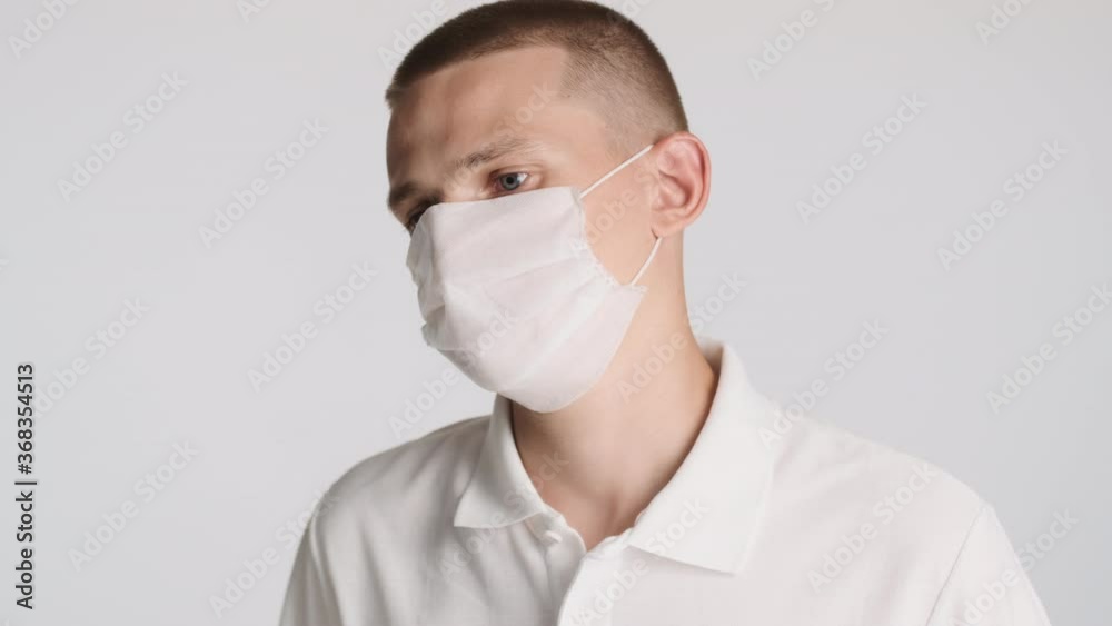 Young casual man in medical mask thoughtfully looking around over white background. Safety concept Young casual man in medical mask thoughtfully looking around over white background. Safety concept