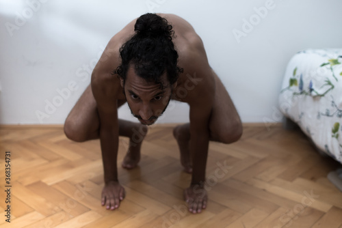 A young Afro European male Yogi does meditation and Hatha Yoga workout at home during lockdown.