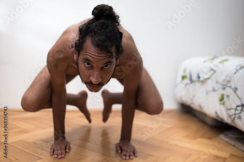 A young Afro European male Yogi does meditation and Hatha Yoga workout at home during lockdown. photo