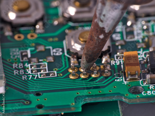 
Soldering iron and circuit board macro photograph. Science and technology themes