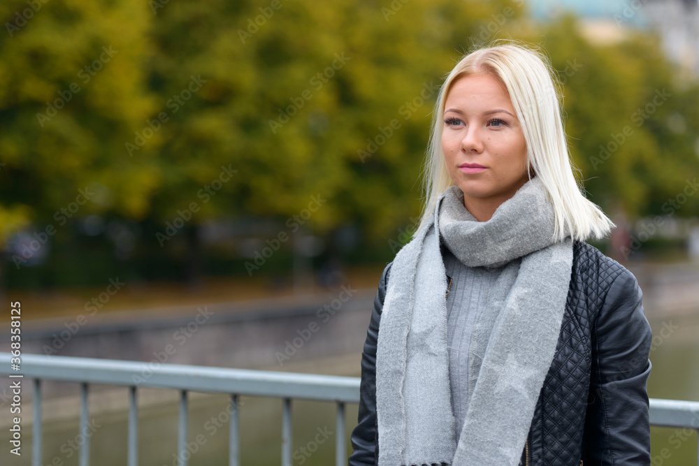 Young beautiful blonde woman thinking on the bridge along the river Young beautiful blonde woman thinking on the bridge along the river