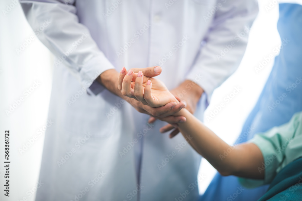 Close up doctor holding a patients hand, representing comfort, hope, warmth and closure, in an medical office room