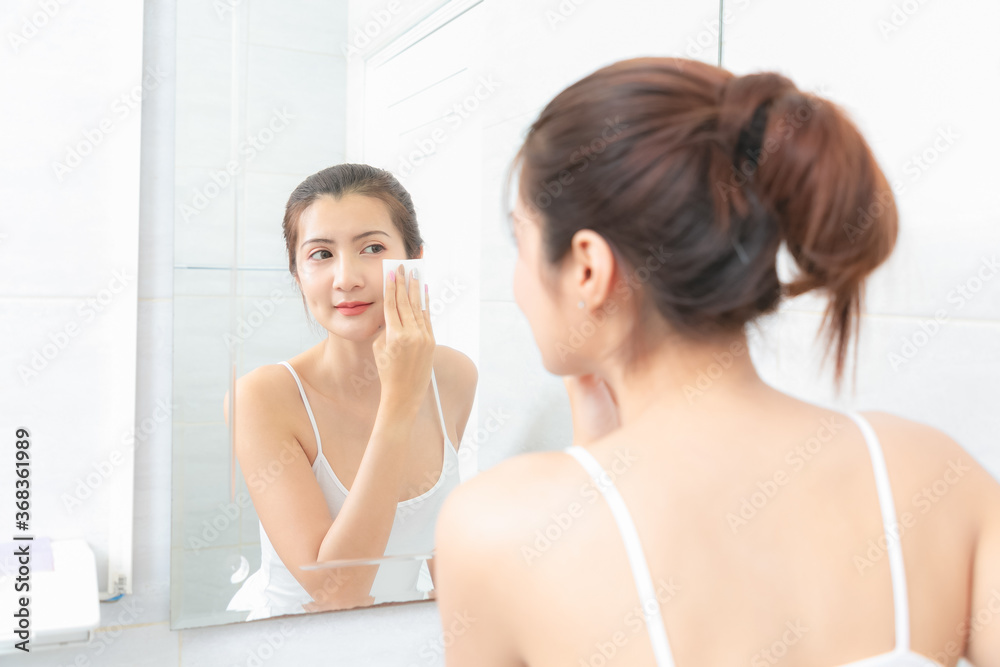 Beautiful Asian Woman applying cosmetic cream in bathroom. Beautiful Asian Woman applying cosmetic cream in bathroom.