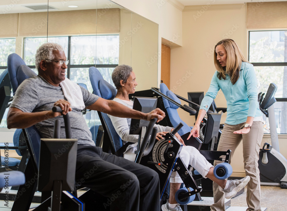 senior couple exercising with trainer in gym senior couple exercising with trainer in gym