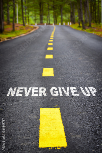 Never give up word on asphalt road surface with marking lines, business success concept and positive challenge emotion idea