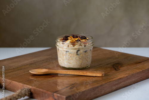 Tableau sur toile Dried oranges and raisins overnight oats on brown wooden board and a spoon, sele